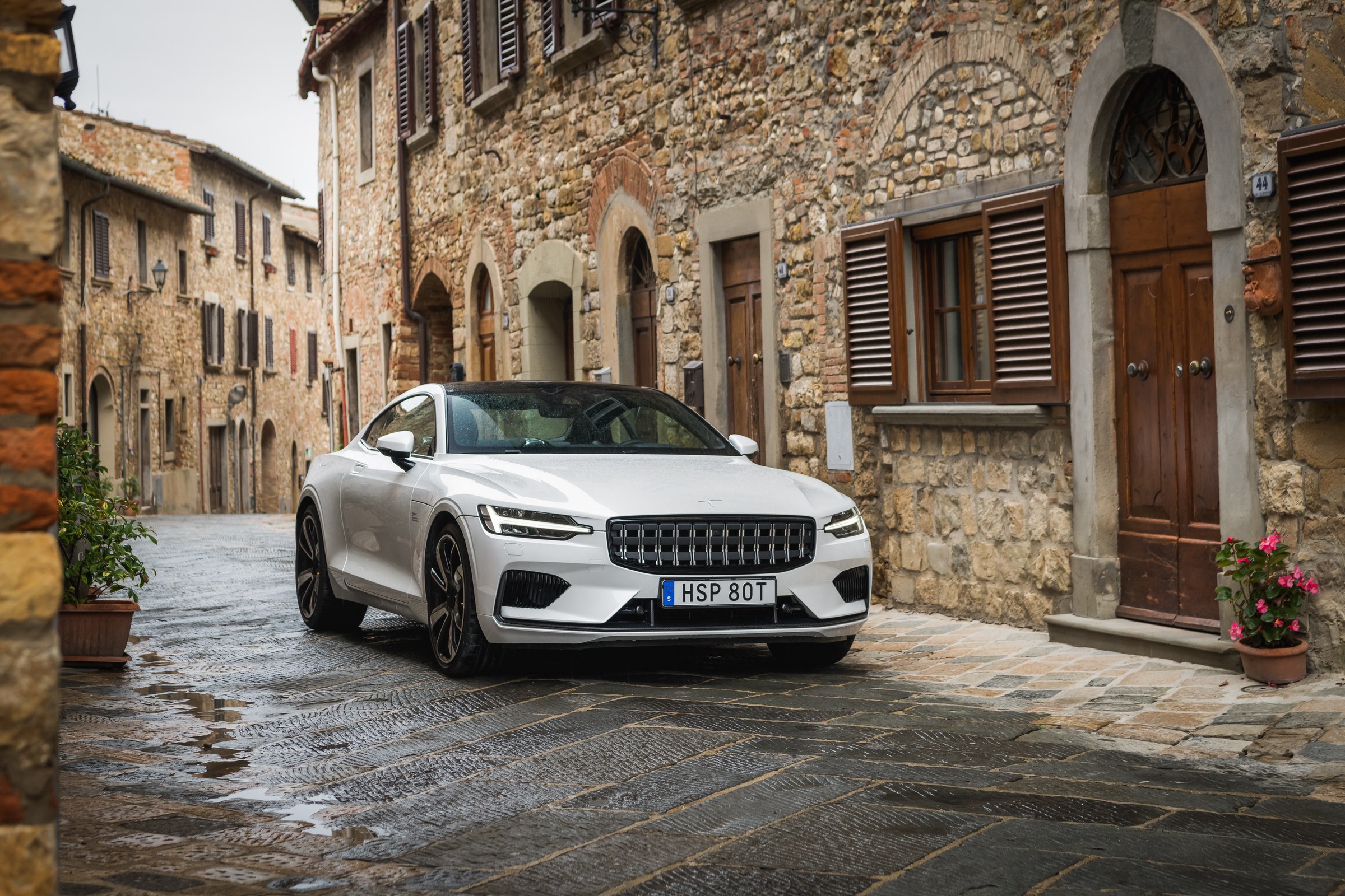 Polestar 1 branco, visto de três quartos dianteiros numa rua empedrada.