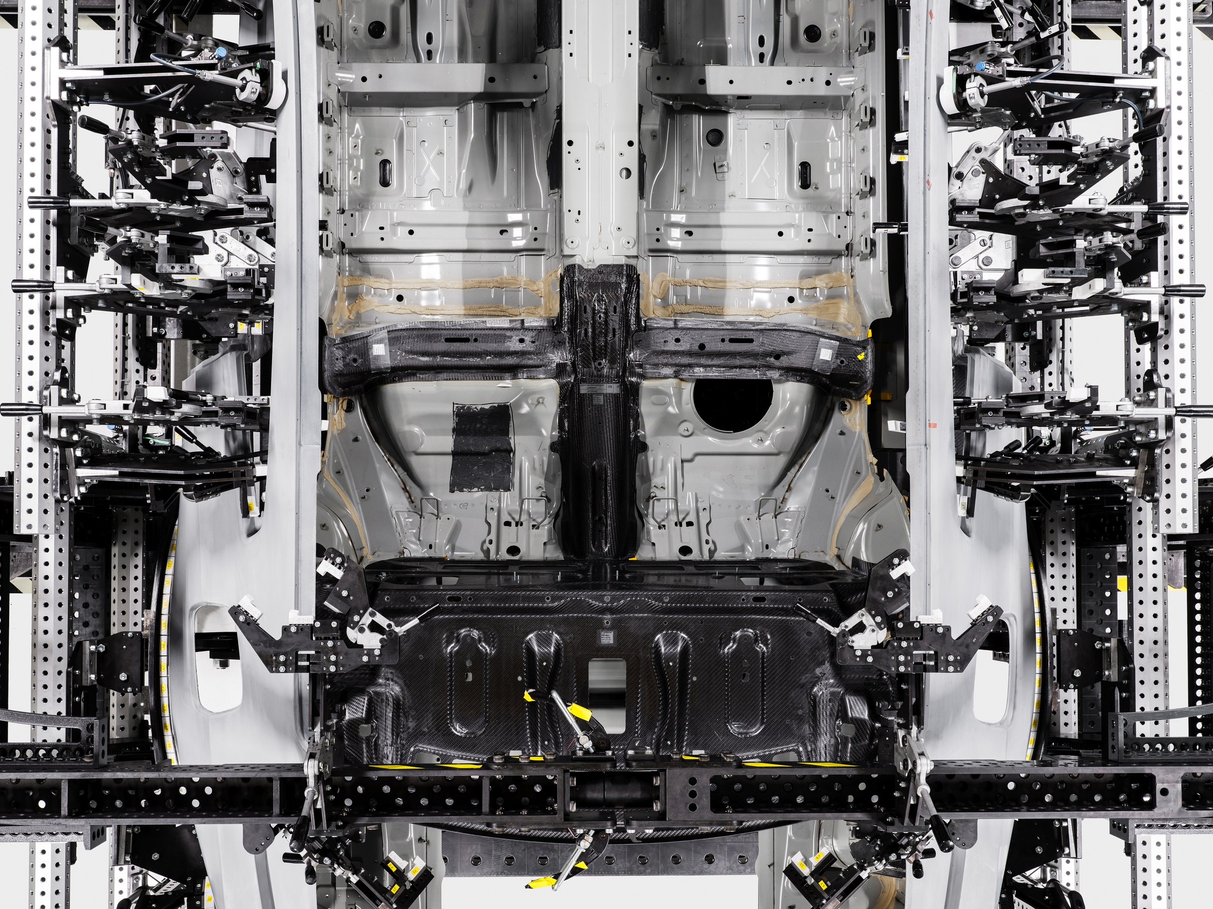 Estrutura inferior do Polestar 1 colocada verticalmente num dispositivo de fabrico.