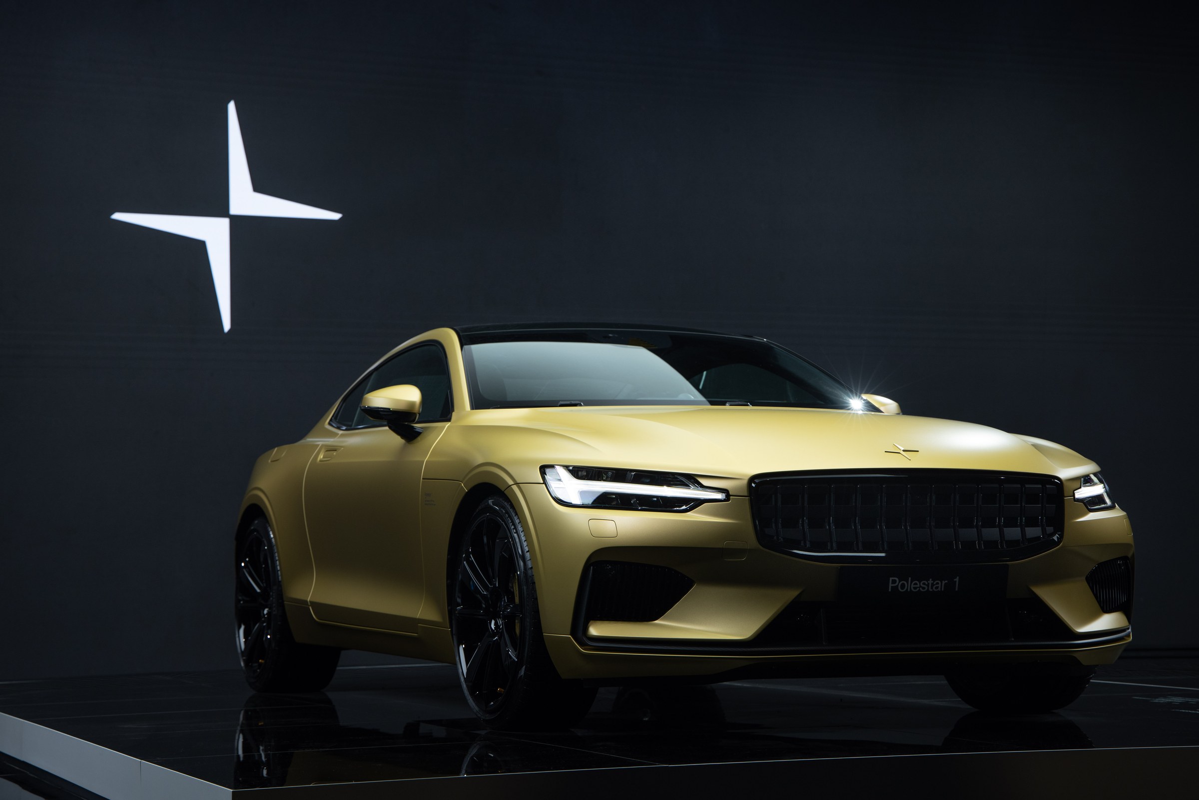 Polestar 1 dourado mate em estúdio, visto de três quartos dianteiros.
