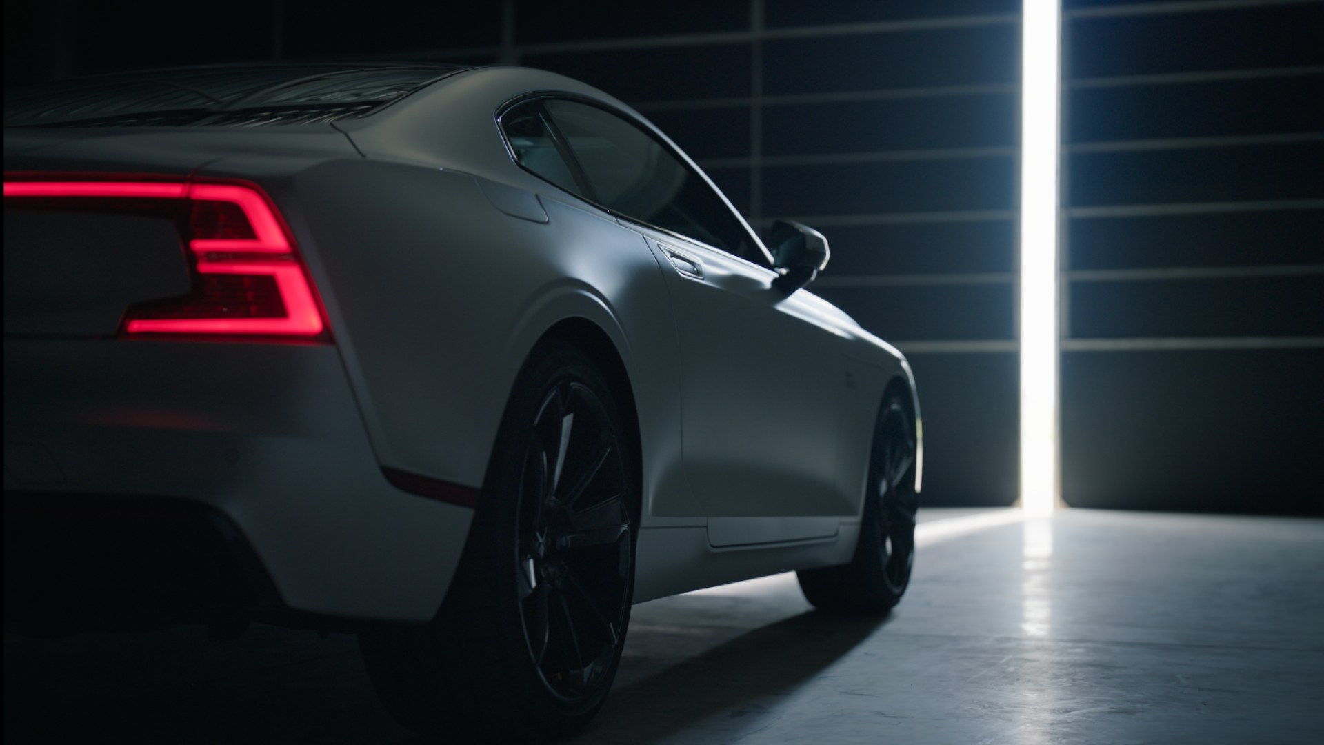 Polestar 1 visto de três quartos traseiros num espaço escuro com faixas de luz.